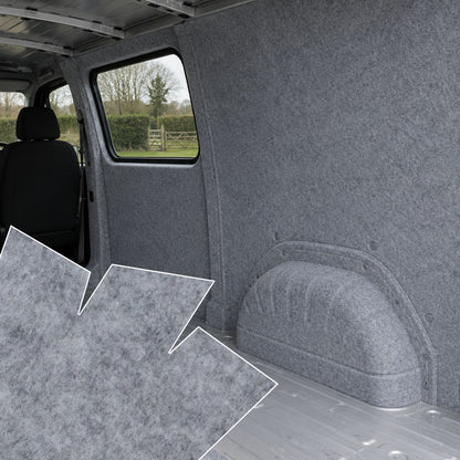 Gray interior of a vehicle with carpeted floor and walls, showing a view through the window.