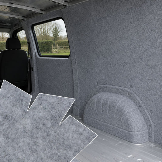 Gray interior of a vehicle with carpeted floor and walls, showing a view through the window.